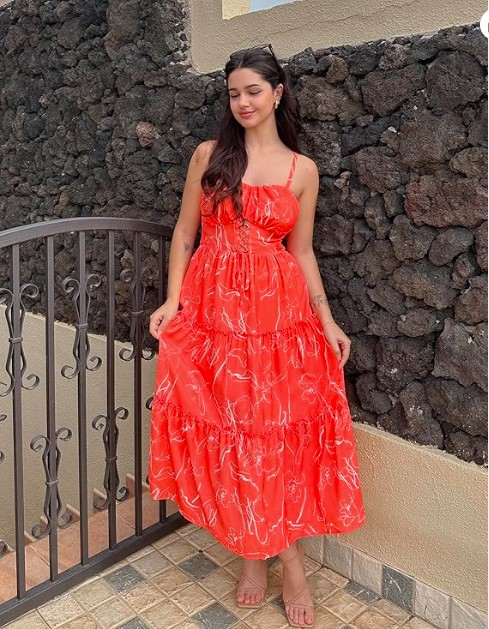 With thin spaghetti straps, a gathered bust with delicate tie detail, and three flowy tiered layers, this dress screams vacation energy. The bold red color with soft white floral line print makes it instantly eye-catching — exactly what you want for summer photos. It's the kind of dress that gets compliments without you trying. Wear it to a rooftop dinner, a beach boardwalk, or a weekend getaway. Pair it with simple nude sandals just like the model, and you're completely done. Why you'll love it: Flowy tiered skirt gives you that carefree summer silhouette Adjustable straps for the perfect fit Bold red color that photographs beautifully Versatile enough for day or evening wear Shop On Amazon